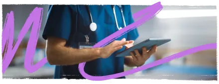 Medical doctor wearing blue scrubs uniform and stethoscope around neck using a tablet.