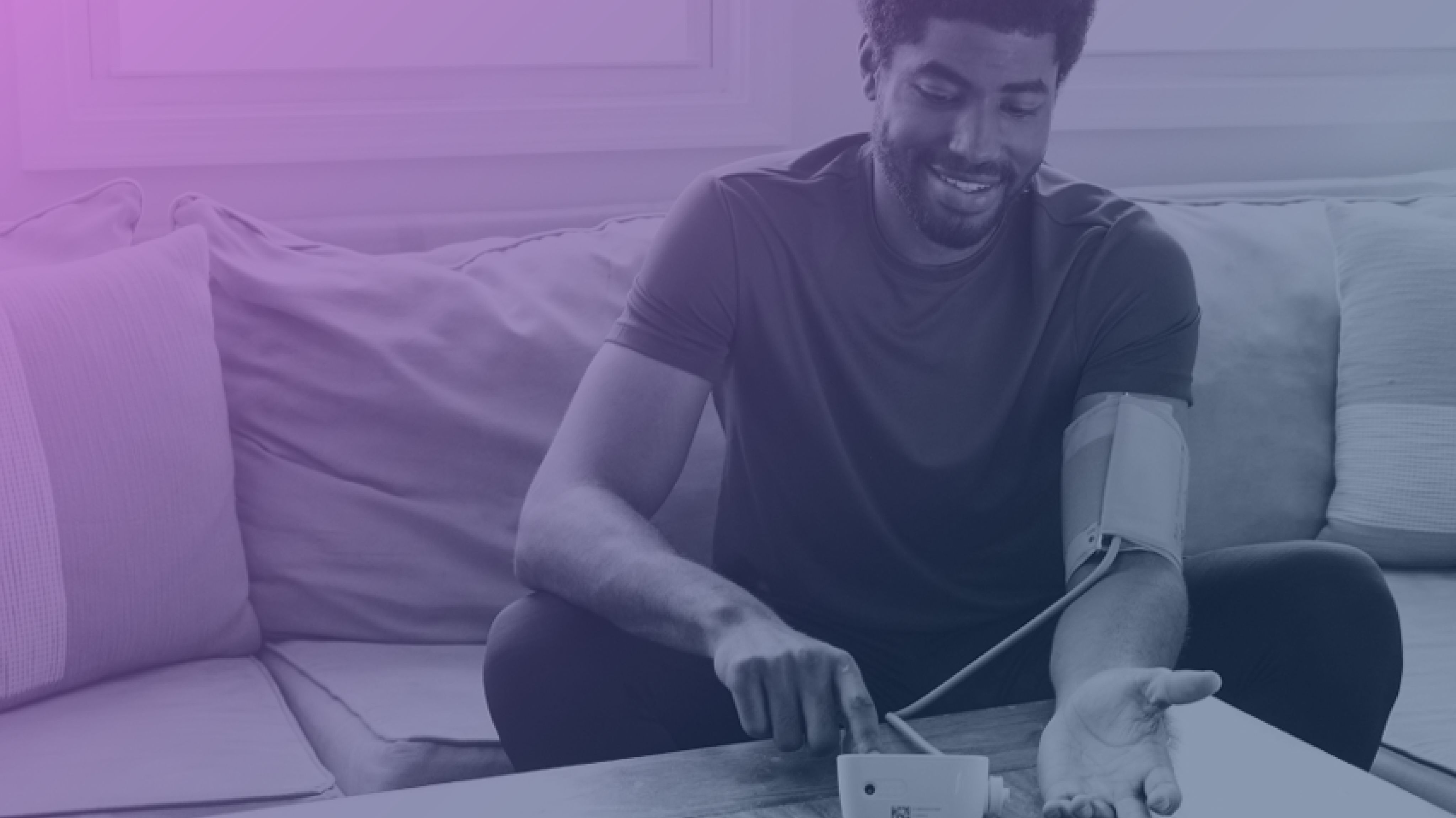 Man at home using a digital blood pressure monitor, appearing content and engaged in self-health monitoring.