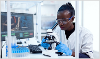 a scientist in a lab looking through a microscope
