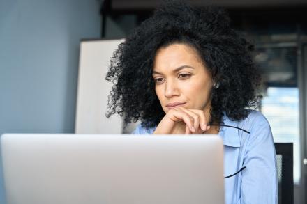 black woman on laptop thinking hard