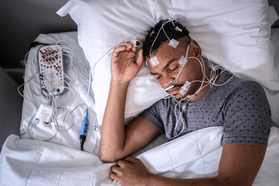 Un hombre se realiza una prueba de polisomnografía, también conocida como estudio del sueño, que mide la actividad del cerebro y del cuerpo durante el sueño.