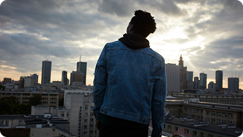 Photograph of a young person overlooking a city skyline with a bright sun in the background