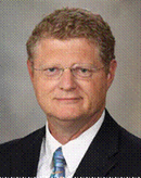Man in a suit and tie wearing glasses.