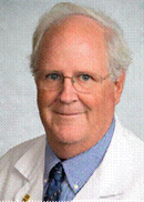 Man with white hair and glasses wearing a dress shirt and tie.