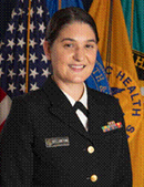 U.S. Public Health Service officer in dress uniform with flags in the background.