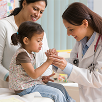 Female doctor examining toddler girl's finger