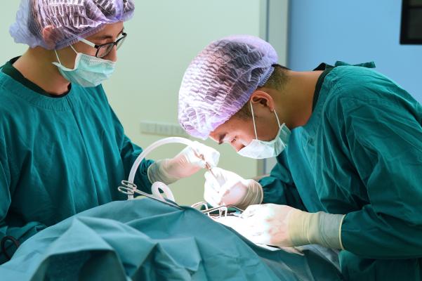 Two surgeons operate on a patient in an operating room.
