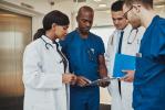 Photo of four physicians discussing a patient's chart information.